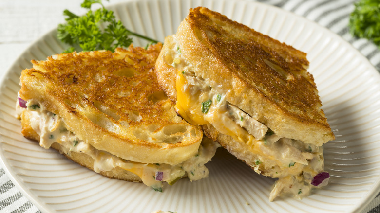 Toasted tuna melt sandwich halved on a white plate.