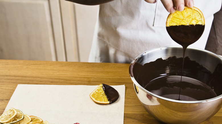A person dipping cookie in chocolate.