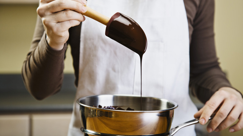 A person melting chocolate in a pot.