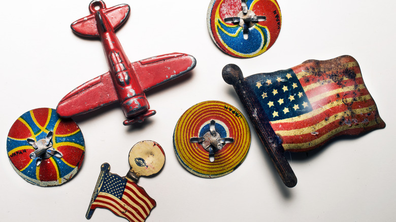A series of small metal vintage cracker jack toys, including a pin, a flag, and and airplane