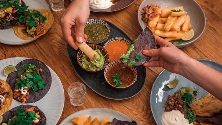 People sharing salsa with Mexican food