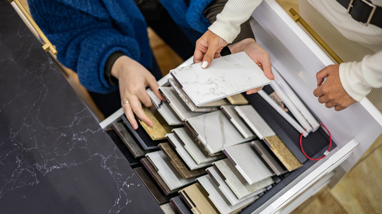 Two sets of hands pick out countertop swatches
