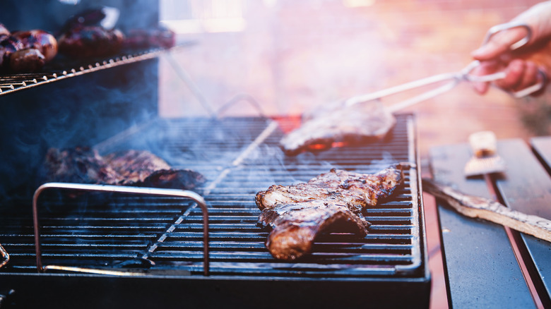 A close-up of beef steaks cooking on grill during a backyard barbecue.