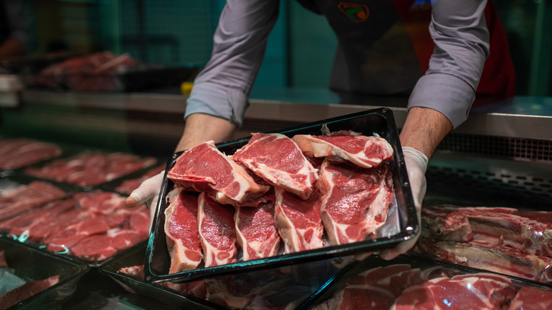 A butcher holds a platter of steak cuts