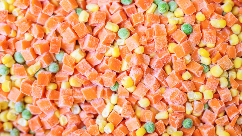 Frozen cubed carrots, corn kernels, and peas in close-up
