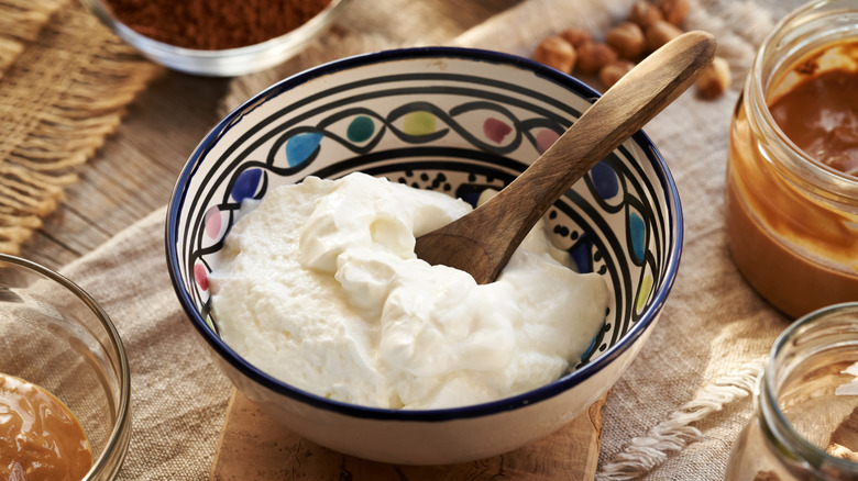 A colorful ceramic bowl filled with yogurt and a wooden spoon