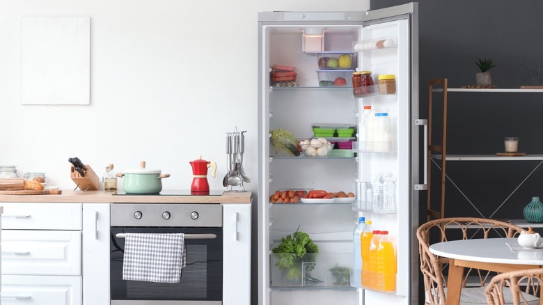 An open refrigerator displaying various items inside a well-appointed kitchen.