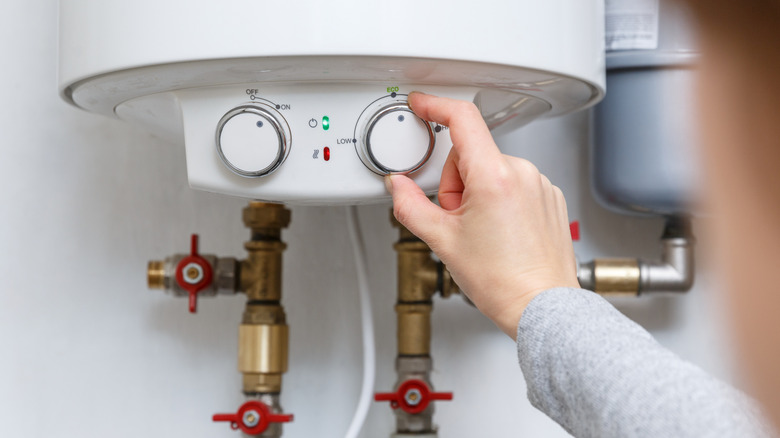 hand adjusts hot water heater temperature