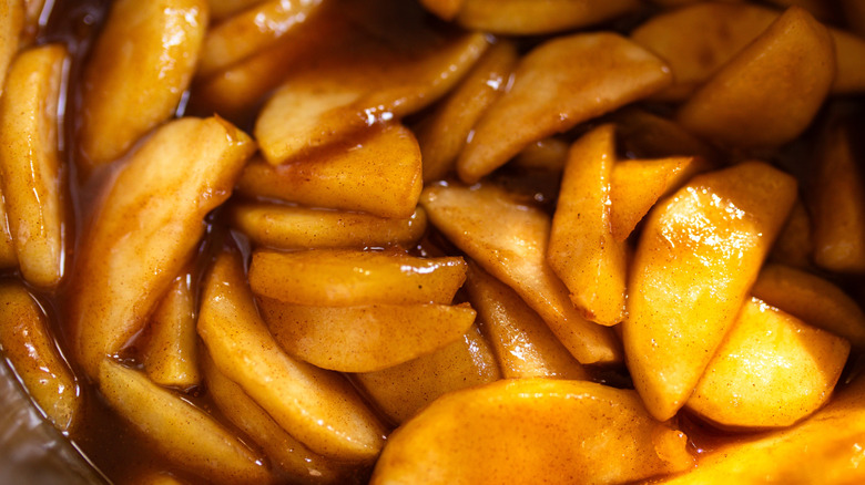Cooked apple pie filling showing sliced apples with a brown cinnamon-rich sauce
