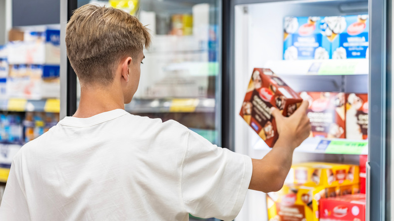 A person pulling out frozen food from a grocery store freezer