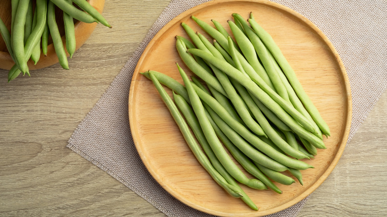 person holding handful of green beans at store