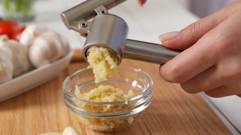 Crushing garlic into a dish with a garlic press