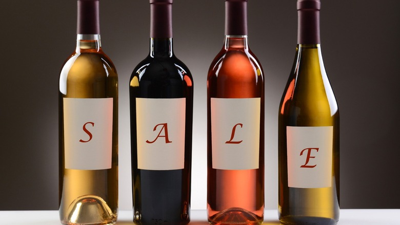 Four bottle of wine spelling out "SALE" with each letter labeled on the bottles