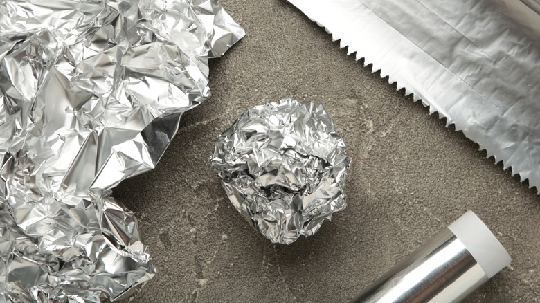 Aluminum foil ball and roll on dark surface