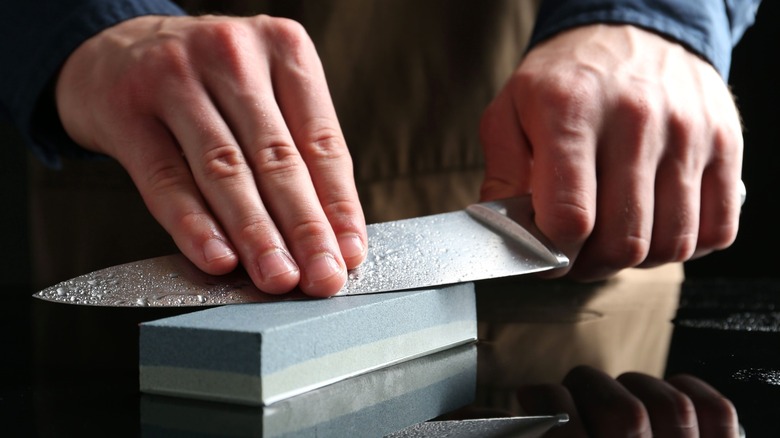Person using whetstone to sharpen knife