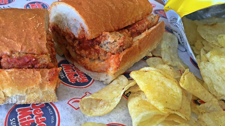 A sliced Jersey Mike's meatball sub with potato chips on a sandwich wrapper