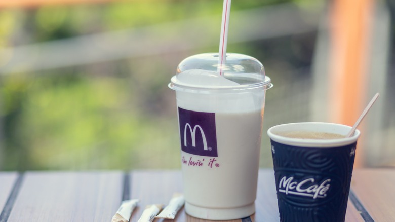 A McDonald's shake next to a cup of McDonald's coffee.