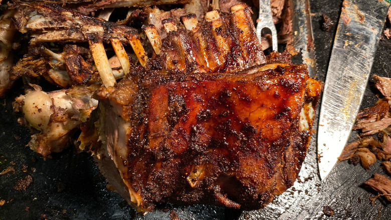 A rack of BBQ goat ribs with a knife and bones in the background