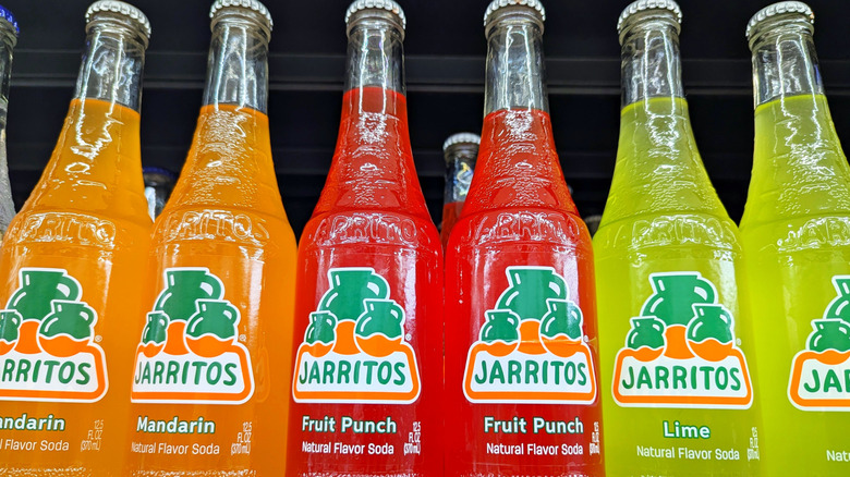 Different flavors of Jarritos bottles lined up on shelf