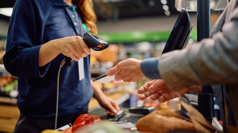 A grocery store worker scanning a digital coupon on a customer's phone.