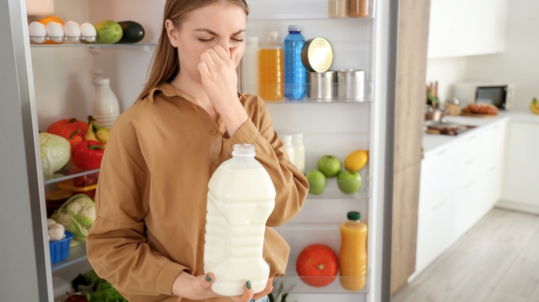 Woman pinches her nose because the spoiled milk stinks