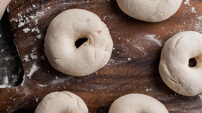Raw bagels on a cutting board.