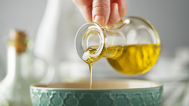 hand pouring olive oil into bowl
