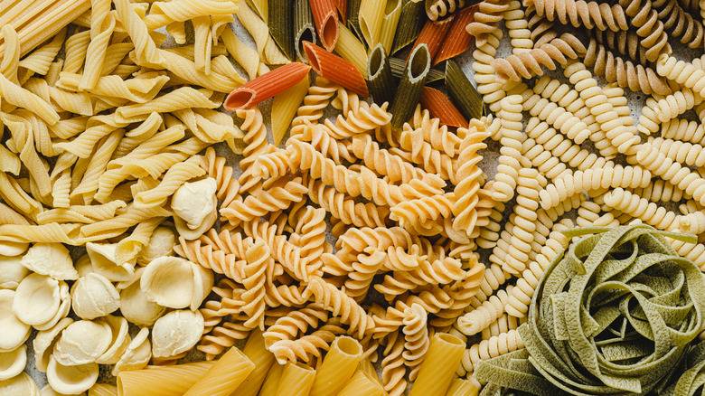 An assortment of dried pasta shapes, like rigatoni, penne, and rotini