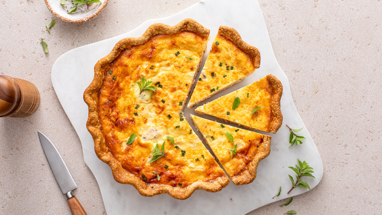 Top view of a whole quiche with fresh herbs