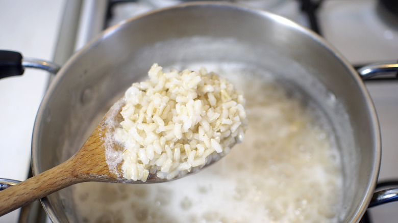 Rice cooking in a pot, with evidence of the starches present in the water.