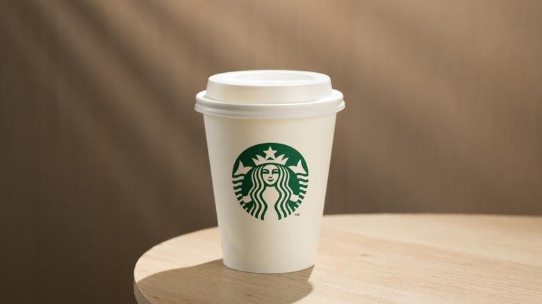 A cup of Starbucks coffee sitting on a wooden table.