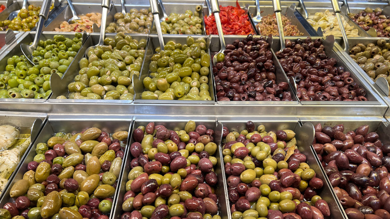 A fresh olive bar in a grocery store with a mixture of green and black olives.