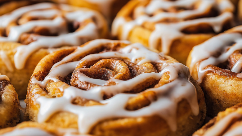 Several golden cinnamon rolls with white icing