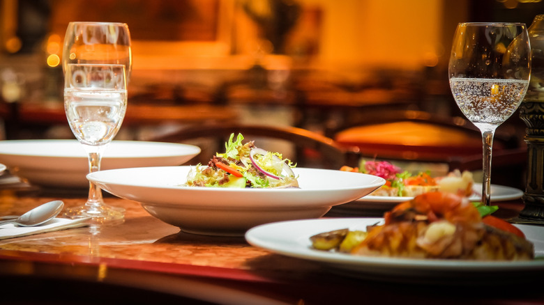 A table at a restaurant with wine glasses and entrees on it