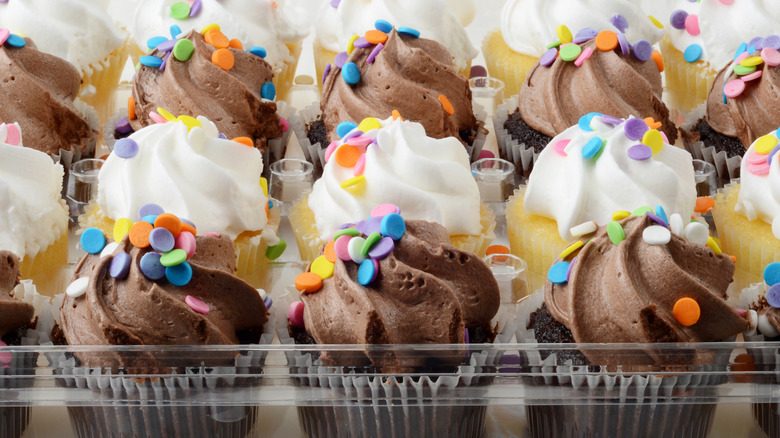 Plastic container of store-bought vanilla and chocolate cupcakes