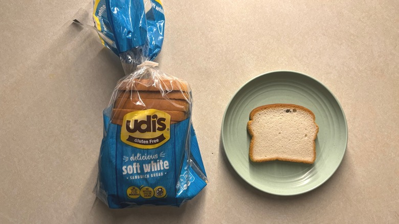 A bag of Udi's gluten free bread next to a slice of bread on a plate.