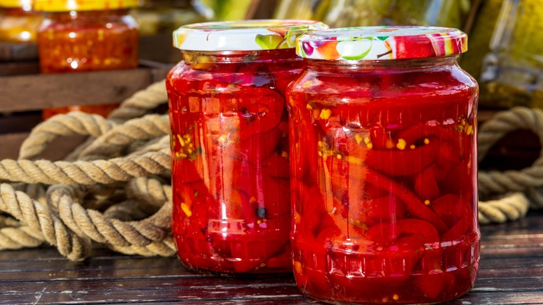 red peppers pickling in jars outside