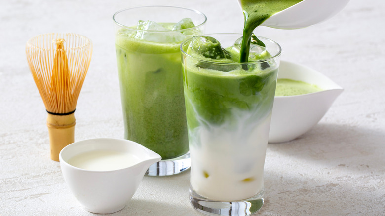Two matcha lattes with bamboo whisk