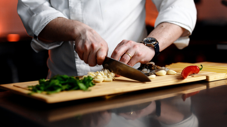 Chef chopping vegetables on a wooden cutting board