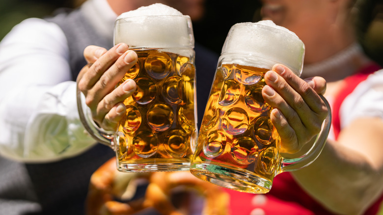 Couple holding beer steins at an Oktoberfest celebration.