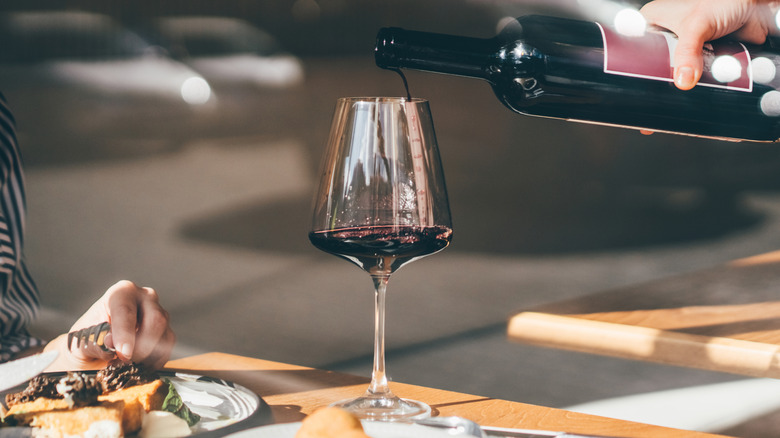 Hand pouring red wine into glass