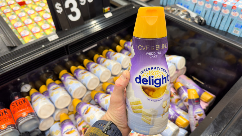 A person holding a bottle of International Delight Coffee Creamer inside a grocery store