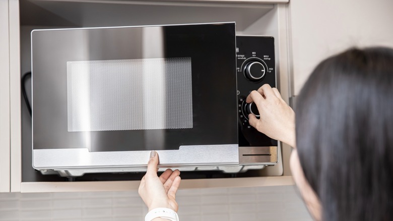Person setting timer on microwave