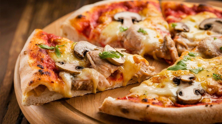 A slice is removed from a pizza with mushroom and cheese