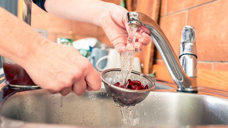 Kidney beans in strainer under running water
