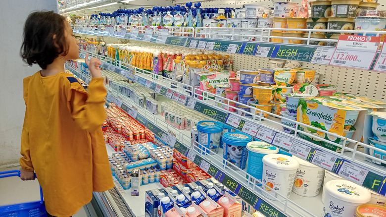 A young girl browsing in a dairy aisle of the supermarket