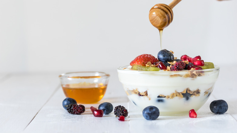 A bowl of yogurt with fruit and honey