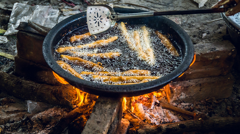 Food being fried over a makeshift fire