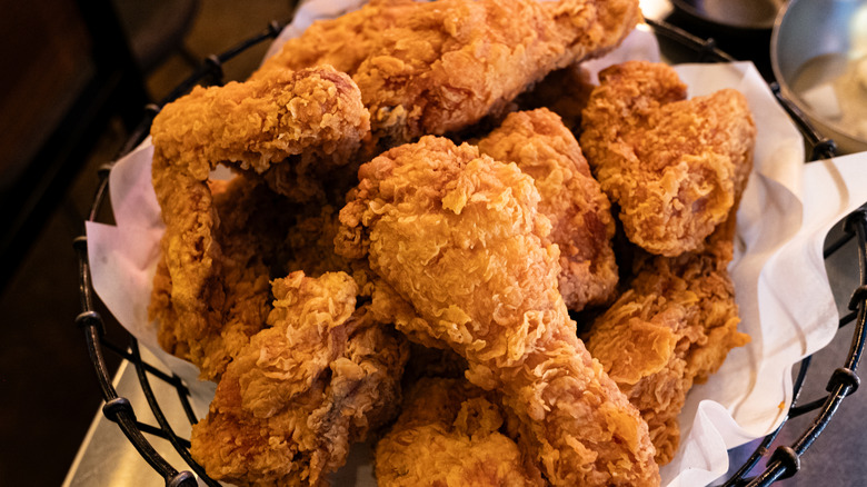 A black, wire basket of golden fried chicken pieces; crisped to perfection