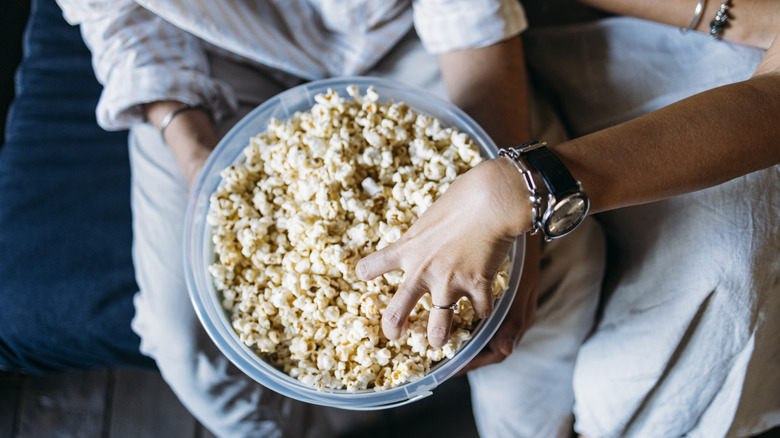 Someone's hand in a large bowl of popcorn